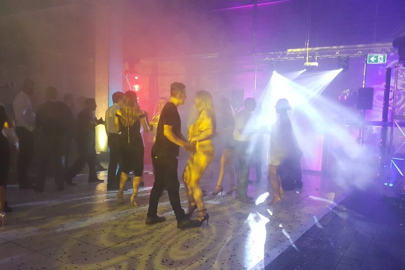 Guests dancing under beam lighting and haze at a Sydney event