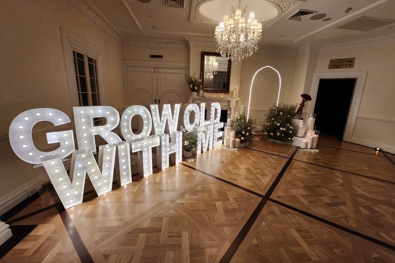 Marquee letters spelling GROW OLD WITH ME beside a parquet dance floor