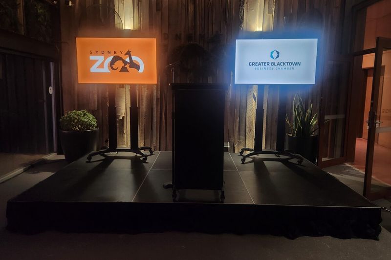 Two large presentation screens running client branding in a darkened room