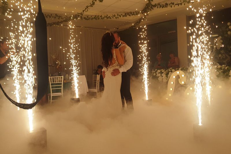 Couple dancing under a floral hoop arch between cold sparkler fountains