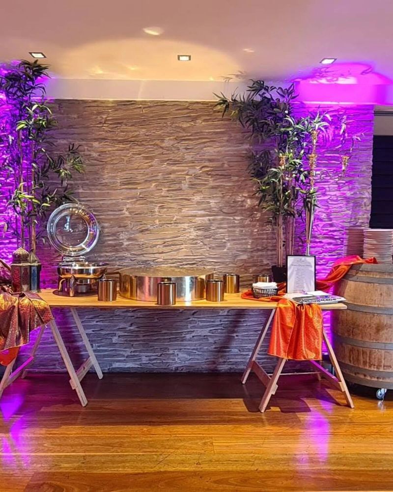 Styled bar against a stone wall with copper vessels, barrel and purple uplighting
