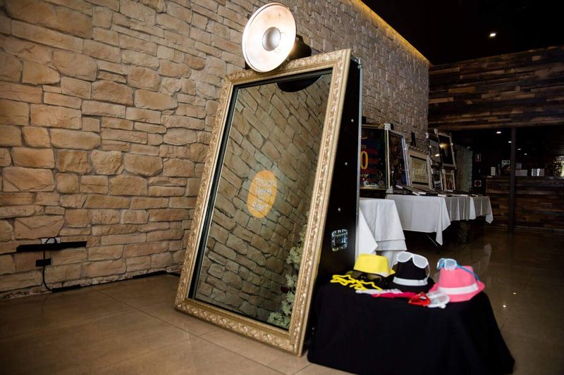 Gold-framed mirror booth with a props table alongside