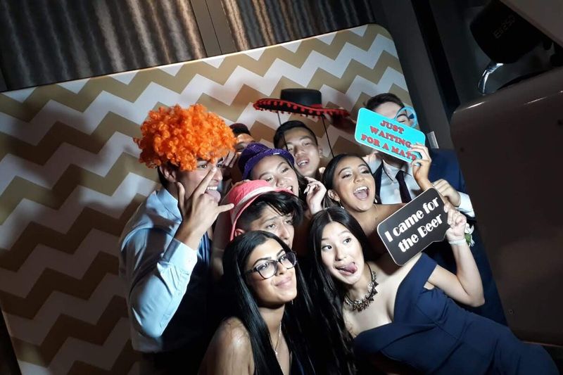 Large group crowded into the booth wearing wigs and holding props