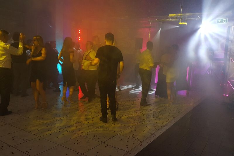 Crowd dancing in haze under warm beam lighting at a party