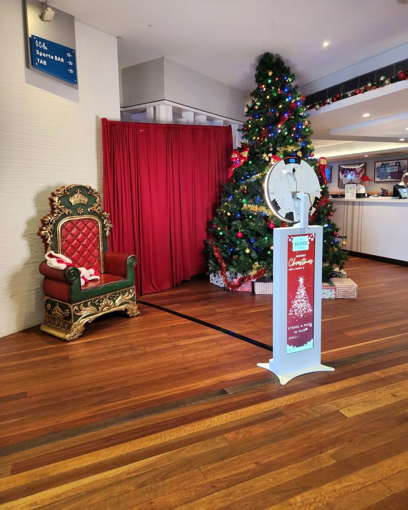 Christmas photo booth set-up with a Santa chair, red drape and decorated tree