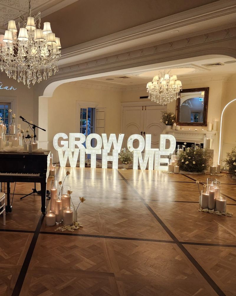 Marquee letters spelling GROW OLD WITH ME at the end of a parquet dance floor