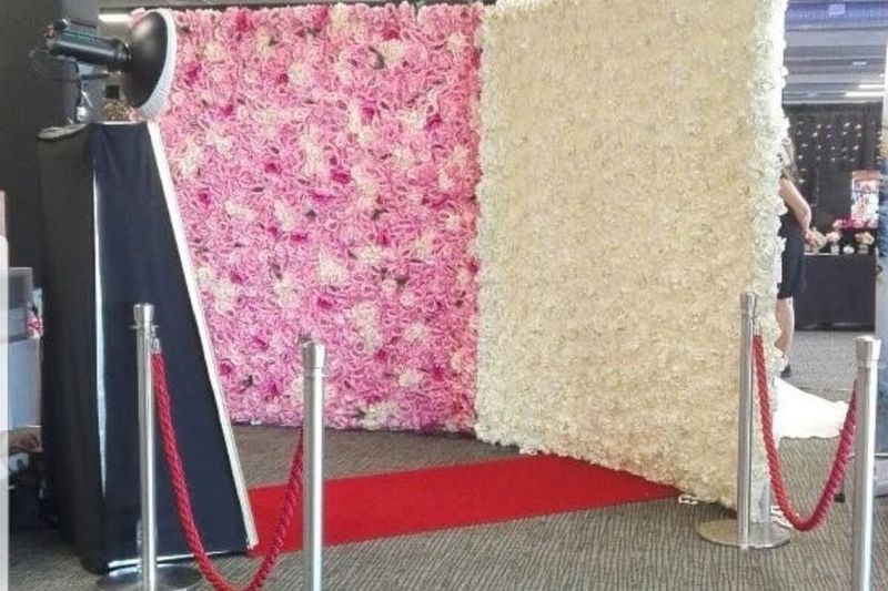 Mirror booth with a pink flower wall, red carpet and rope barrier
