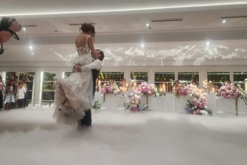 Groom lifting the bride above a dry ice cloud during the first dance