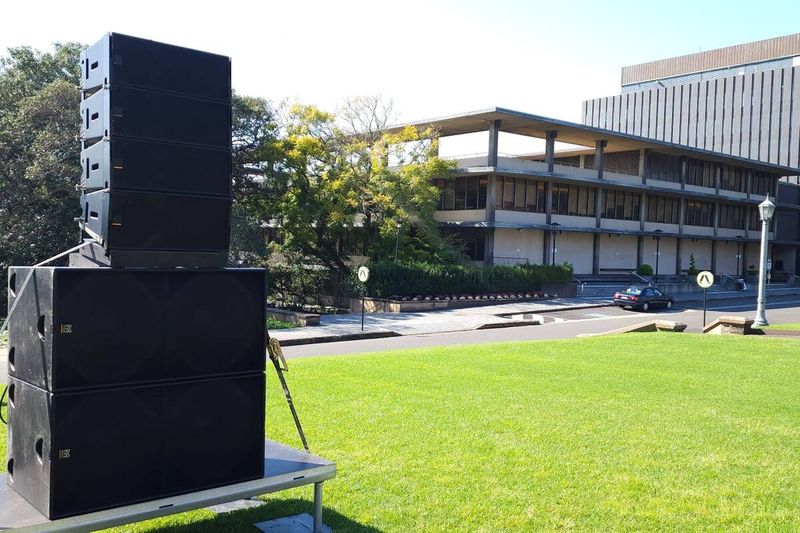 Line array speaker stacks set up on a lawn for an outdoor event