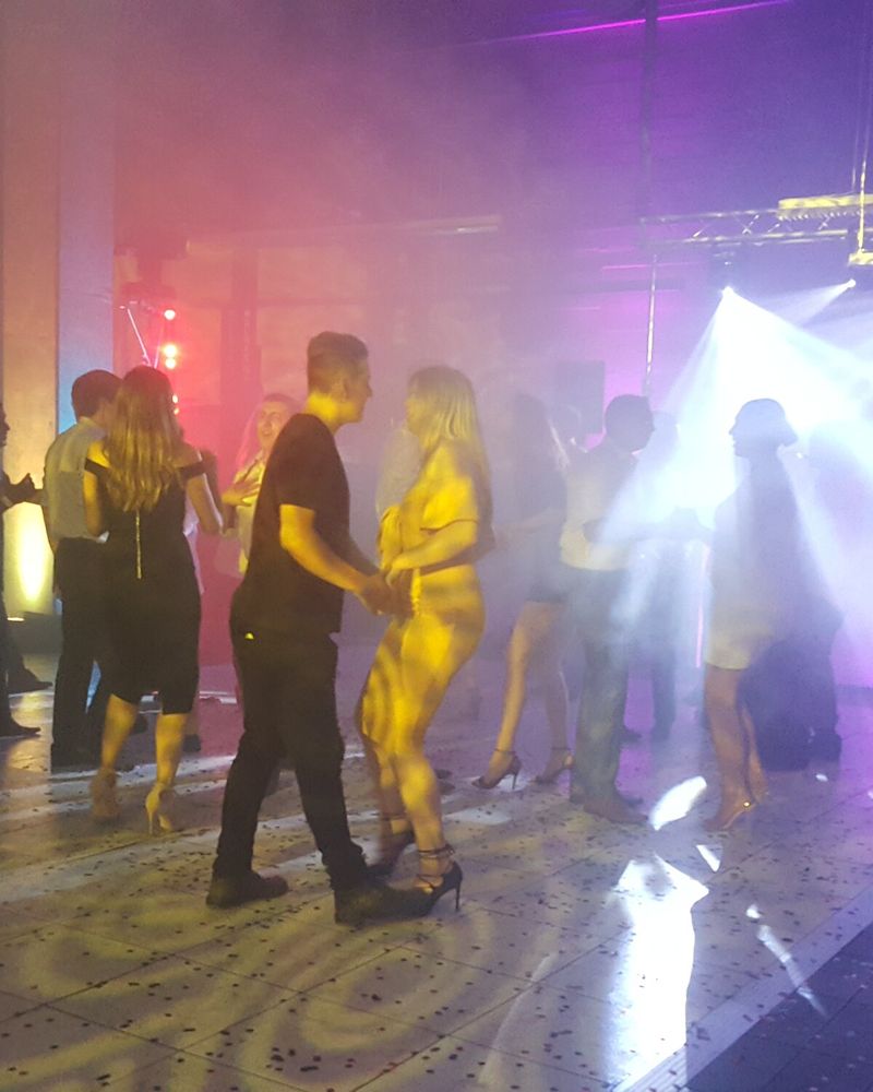Dance floor crowd lit by warm beams and haze at a Sydney event