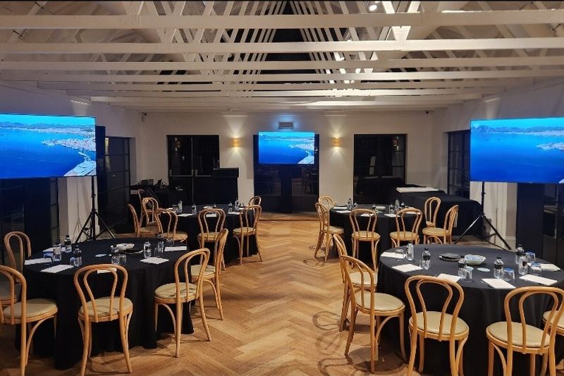 Banquet rounds set in a ballroom with two lit screens