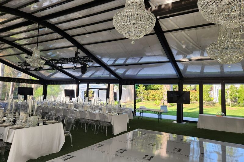 Lighting and speakers rigged from a glass marquee frame above set tables
