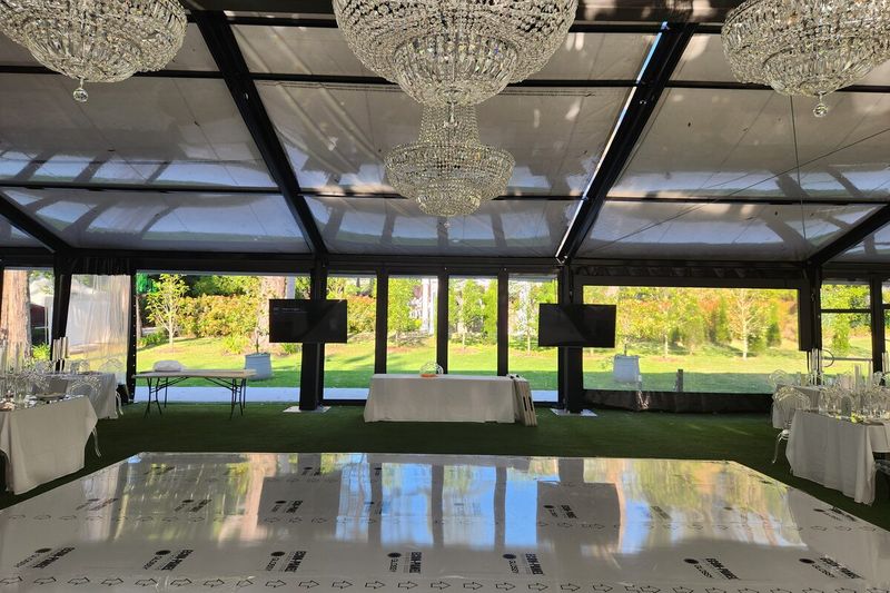 Dance floor laid and lit inside a glass marquee