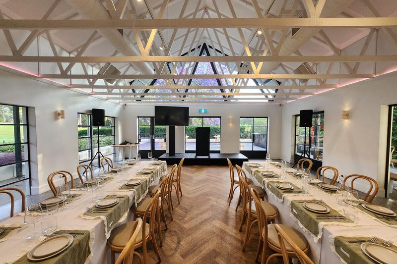 Long tables set under a white-beamed ceiling for a corporate dinner