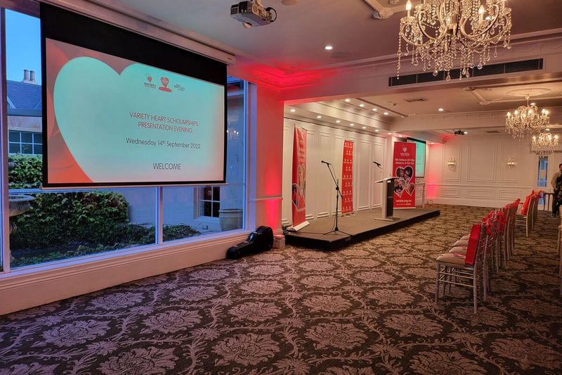 Stage screen showing event graphics with red uplighting either side