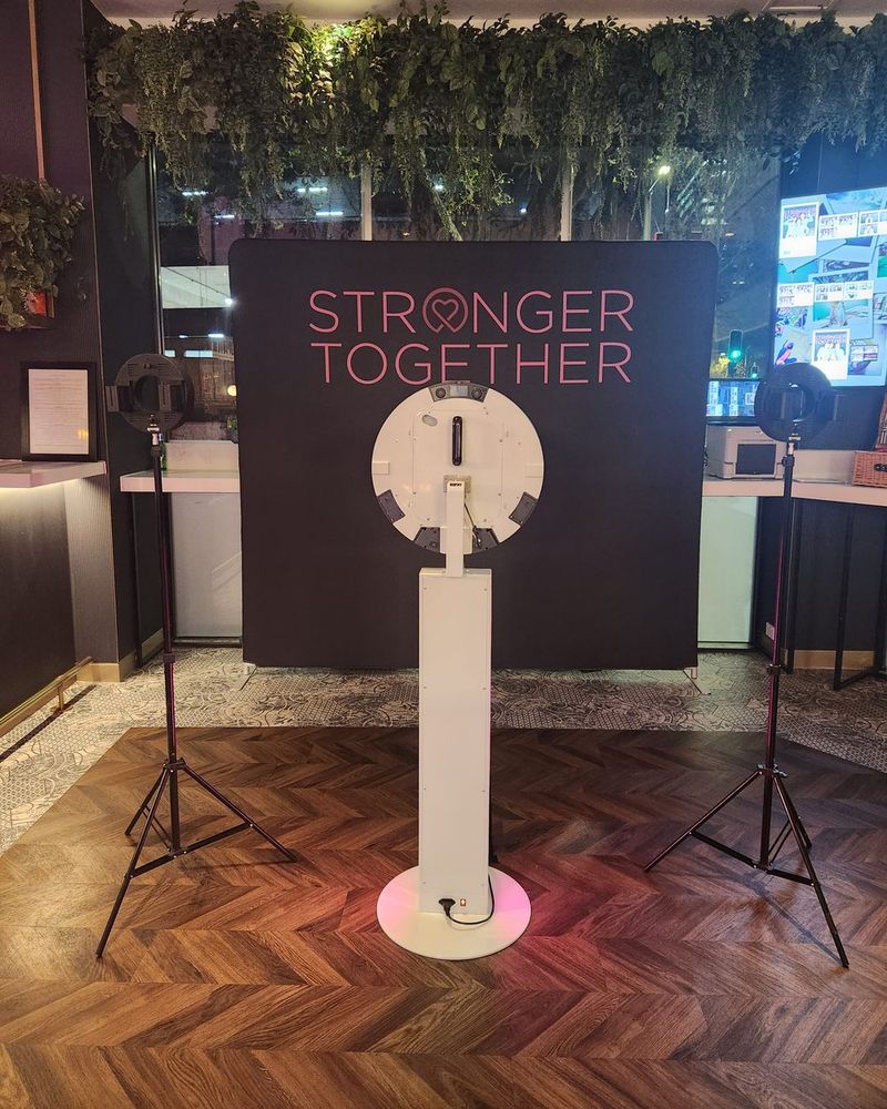 Photo booth with ring lights in front of a custom printed brand backdrop