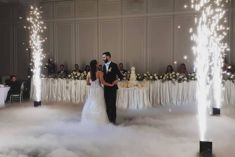 Cold sparkler fountains either side of a couple dancing in a low dry ice cloud in a panelled ballroom