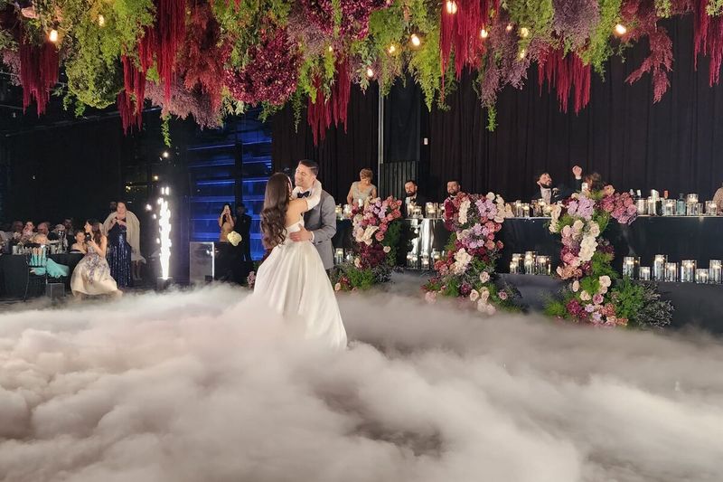 Bride in a dry ice cloud beneath a suspended floral installation