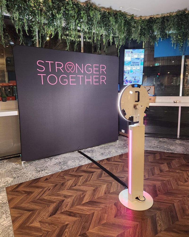 GIF photo booth on a stand beside a custom printed backdrop in a function venue