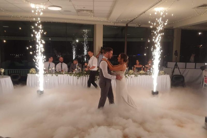 Couple mid-waltz between two cold sparkler fountains