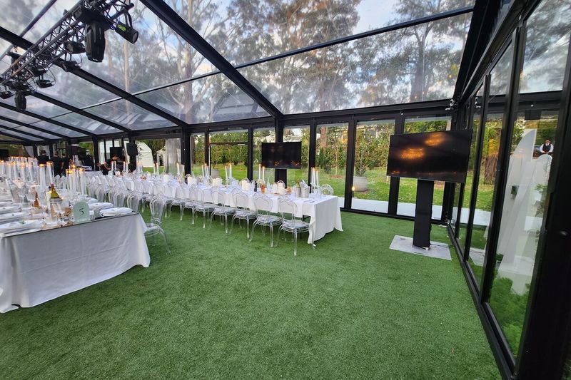 Banquet tables set under a clear glass marquee