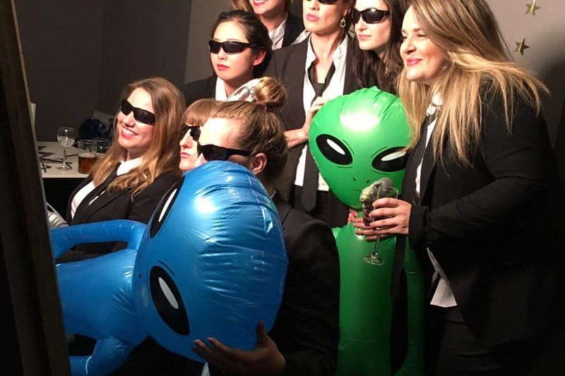 Group of guests posing with sunglasses and inflatable props at the photo booth