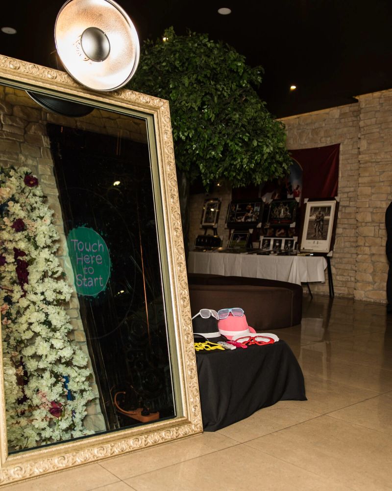 Gold-framed mirror booth beside a flower wall at a Sydney venue