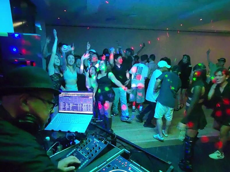 Guests dancing in front of the Charlie Sparx DJ booth at a function
